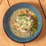 Shrimp ceviche topped with sliced cucumber in a citrus broth, served in a blue bowl