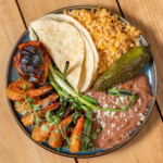 Cajun shrimp plate with rice, refried beans, grilled scallions and a flour tortilla