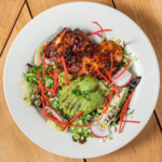 Chipotle BBQ chicken salad with avocado, radish and red peppers on a white plate