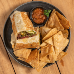 Surf and turf burrito cut in half with tortilla chips and salsa in a black bowl