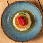 White chocolate and lime flan topped with a strawberry in a blue bowl