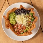 Tostada Verde Crunch in a crisp tortilla bowl with guacamole, black beans, cheese and pico de gallo