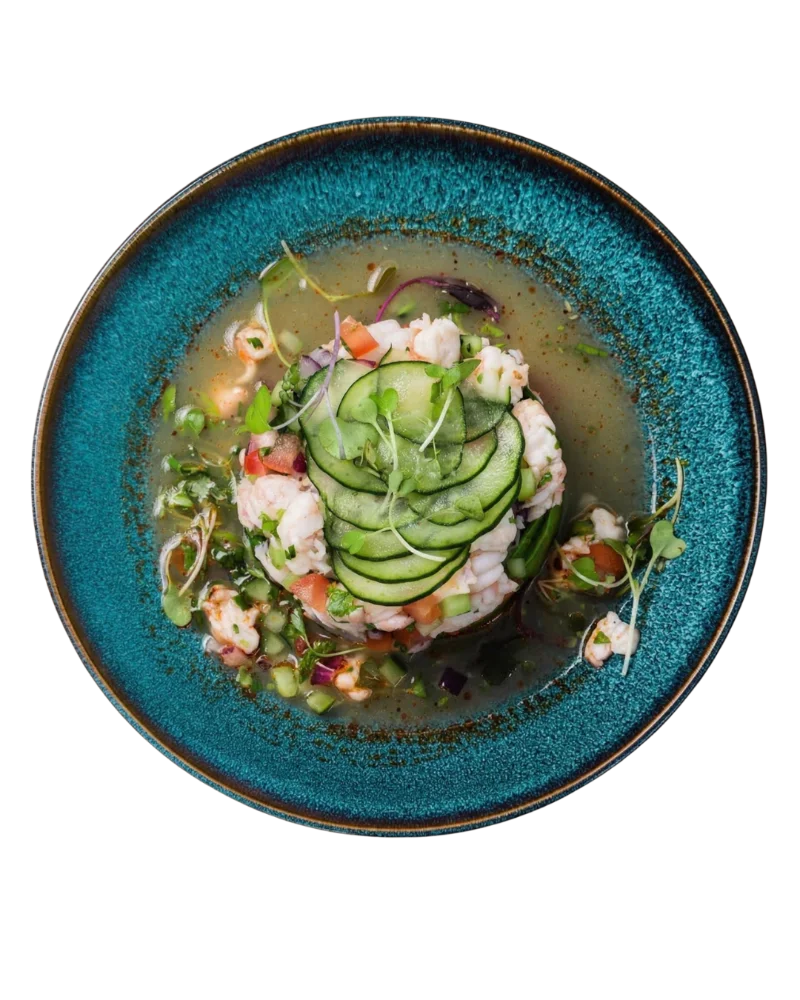Shrimp ceviche with sliced cucumber and microgreens in a teal bowl