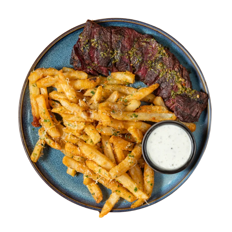 Grilled steak with seasoned fries and a white dipping sauce on a blue plate