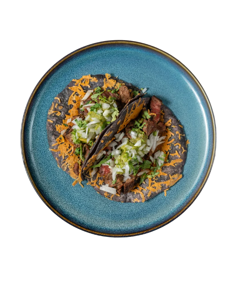 Two tacos topped with shredded cheese and cabbage on a blue plate