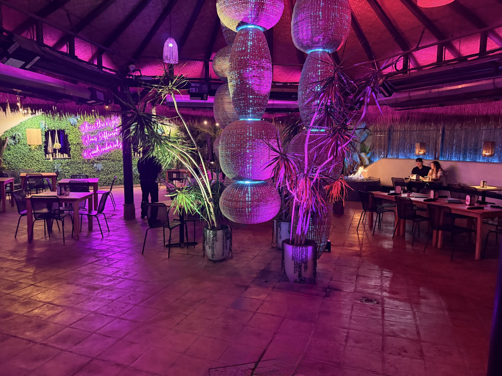 Woven rattan light columns and tall lit trees on the open air patio at Casa de Onda in Costa Mesa