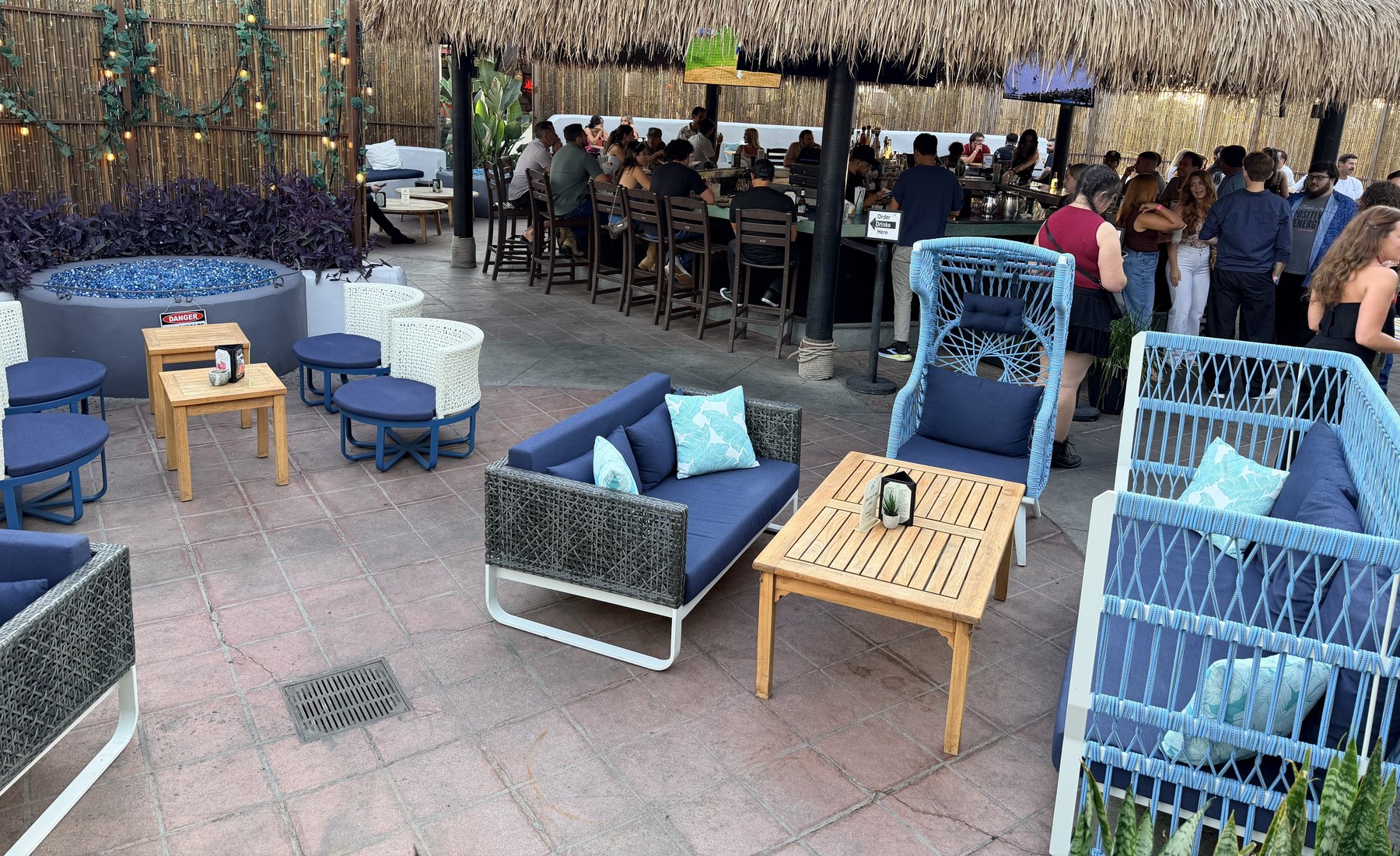 Guests at the thatched roof bar and lounge seating on the open air patio at Casa de Onda in Costa Mesa